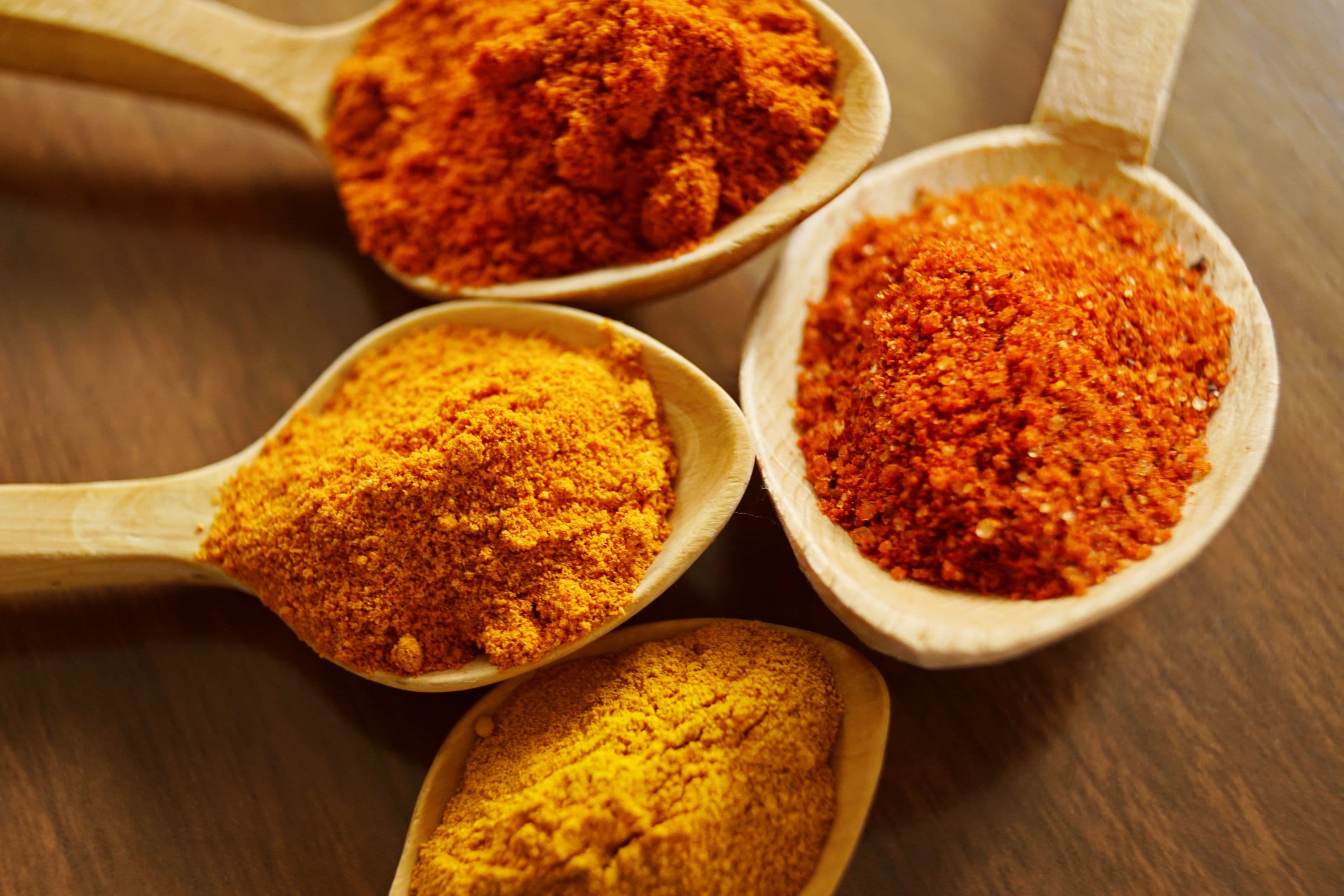 Turmeric and natural spice powders on wooden spoons